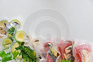 Fillet and vagatables in vacuum bags for sous vide coocing on white marbleized background