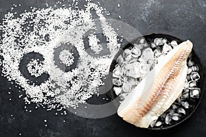 Fillet of white sea cold-water fish cod in ice cubes on a dark background. Top view