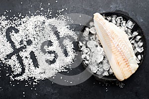 Fillet of white sea cold-water fish cod in ice cubes on a dark background. Top view