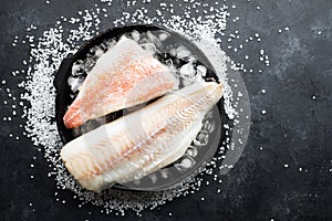 Fillet of white sea cold-water fish cod in ice cubes on a dark background. Top view