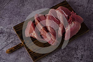 filleted raw pork tenderloin on a wooden board