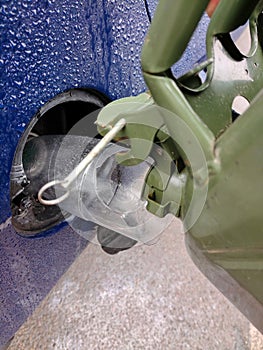 Filling fuel into the gas tank of a car from an iron can close-up