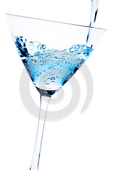 Filling a glass with blue cocktail tilted and bubbles