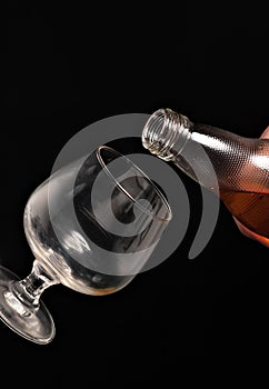 Filling a glass of brandy on a black background.