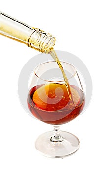 Filling a glass of brandy isolated on white
