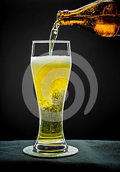 Filling glass glass with golden beer on close up