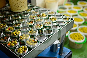 Filling of glass jars with pickled olives