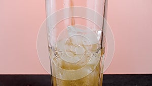 Filling glass with soda water with ice cubes. Action. Close up of pouring soft drink with many bubbles inside the