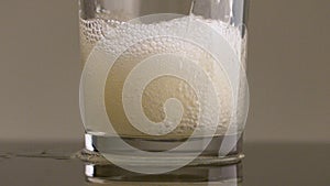 Filling glass with soda water in slow motion. Stock footage. Close up of pouring soft drink with many bubbles inside the
