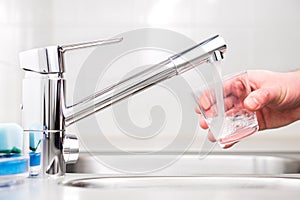 Filling glass with tap water. Modern faucet and sink.