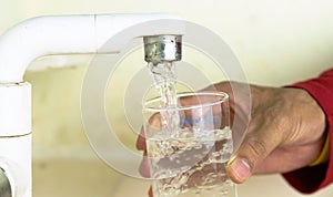 Filling glass with tap water. Modern faucet and sink.