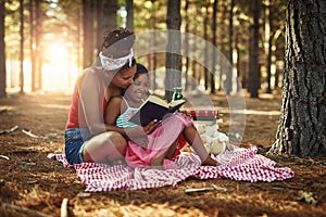 Filling her childhood with imagination and fun. a mother and her little daughter reading a book together in the woods.