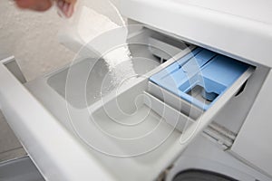 Filling the laundry compartment of the washing machine with white powder to clean the laundry