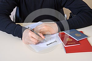 Filling out an employment contract and employment record, passport and diploma on the table