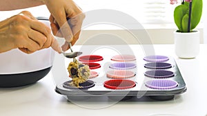 Filling silicone cups with muffin batter close up on white background