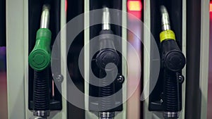 Filling station. A hand returns a fuel nozzles at a gas station at night