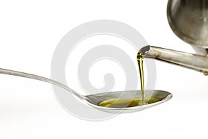 Filling up a tablespoon of extra virgin olive oil from a cruet