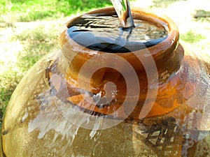 Filling water in a clay pot overflowing in summer during lack of water in rural areas