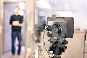 Film camera in broadcasting studio, spotlights and equpiment, director in the background