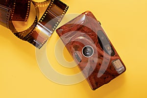 Film camera of red color on a yellow background. The color film, negatives for photographs