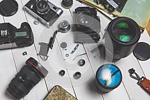 Film cameras, components, digital cameras, and lenses on wooden white background technology development concept