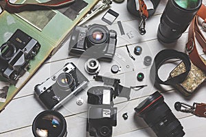 Film cameras, components, digital cameras, and lenses on wooden white background technology development concept