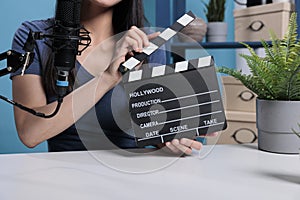 Film director holding movie slate in front of camera recording videoblog