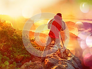 Film effect. Happy photo enthusiast enjoy photography of fall daybreak in nature on cliff on rock. Dreamy fogy landscape