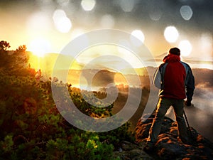 Film effect. Happy photo enthusiast enjoy photography of fall daybreak in nature on cliff on rock. Dreamy fogy landscape