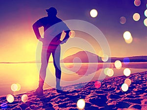 Film effect. Man exercising on the beach. Silhouette of active man exercising and stretching on the lake beach at sunrise.