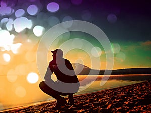 Film effect. Man exercising on the beach. Silhouette of active man exercising and stretching on the lake beach at sunrise.