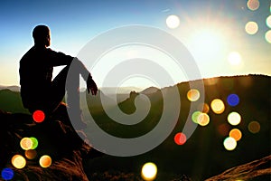 Film grain. Hiker take relaxing on a rock and enjoying sunset at horizon