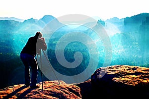 Film grain. Professional on cliff. Nature photographer takes photos with mirror camera on mountaiin peak