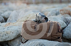 The film medium format camera lies on the stones against the backdrop of a canvas vintage backpack