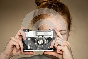 Film retro camera in the beautiful hands of young red-haired girl