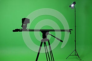 Film studio with a green screen. Tripod with camera, and rails. Shooting studio with green room.