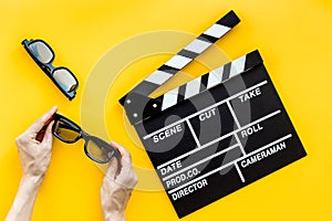 Filmmaker accessories. Clapperboard and glasses on yellow background top view