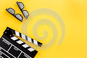 Filmmaker accessories. Clapperboard and glasses on yellow background top view copyspace