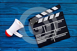 Filmmaker concept. Electronic megaphone and clapperbord on blue wooden background top view