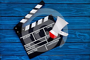 Filmmaker concept. Electronic megaphone and clapperbord on blue wooden background top view