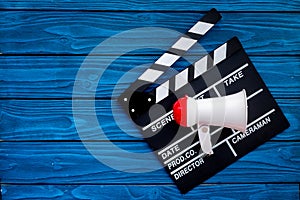 Filmmaker concept. Electronic megaphone and clapperbord on blue wooden background top view copy space