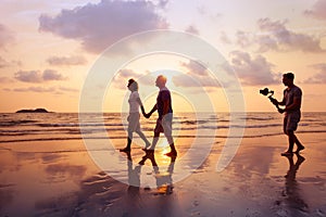 Filmmaker filming video of couple with camera stabilizer on the beach photo