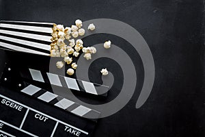 Filmmaker profession with clapperboard and popcorn on black background top view copyspace
