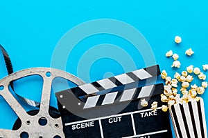 Filmmaker profession with clapperboard, popcorn and video tape on blue background top view copyspace photo