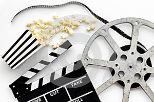 Filmmaker profession with clapperboard, popcorn and video tape on white background top view