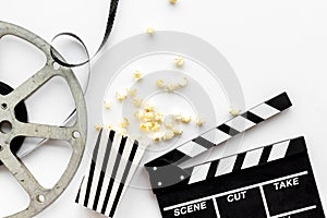 Filmmaker profession with clapperboard, popcorn and video tape on white background top view