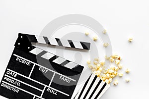 Filmmaker profession with clapperboard and popcorn on white background top view
