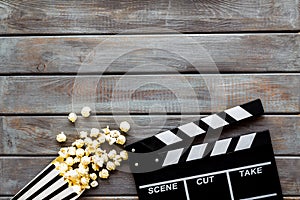 Filmmaker profession with clapperboard and popcorn on wooden background top view copyspace