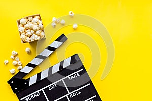 Filmmaker profession with clapperboard and popcorn on yellow background top view copyspace