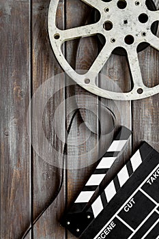 Filmmaker profession with clapperboard and video tape on wooden background top view